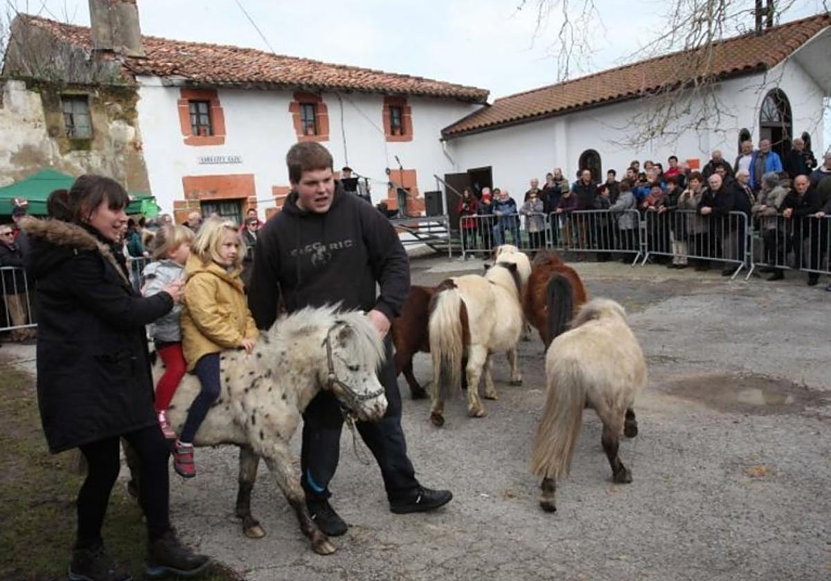 Niñas y niños paseando en pottokas durante una romería.