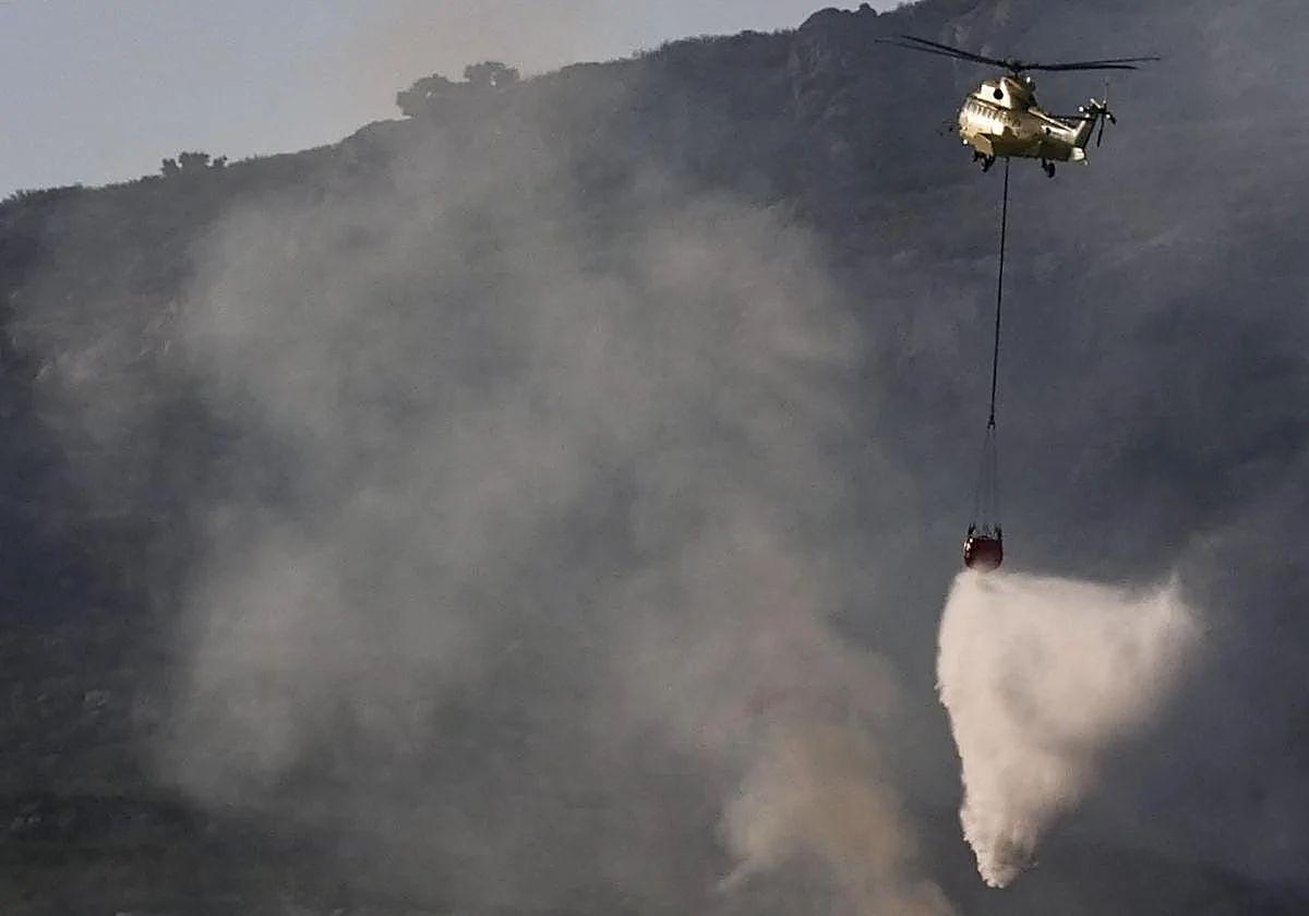 Un helicóptero trabaja en las labores de extinción del incendio que afecta a la Sierra de la Plata, en Tarifa (Cádiz).