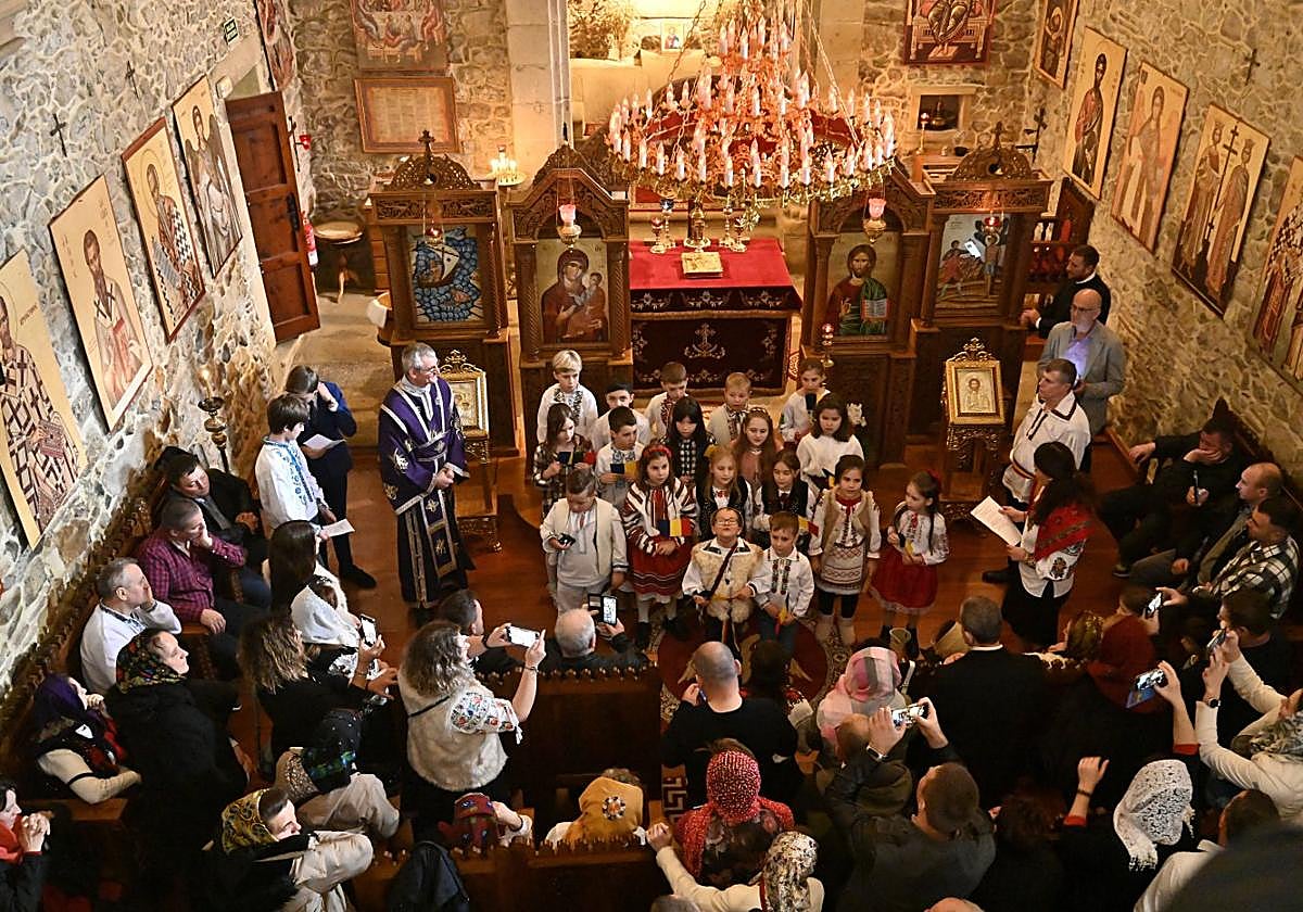 Fieles ortodoxos en la ermita de Uba de Martutene, mientras un coro de niños canta el himno de Rumanía frente al altar.