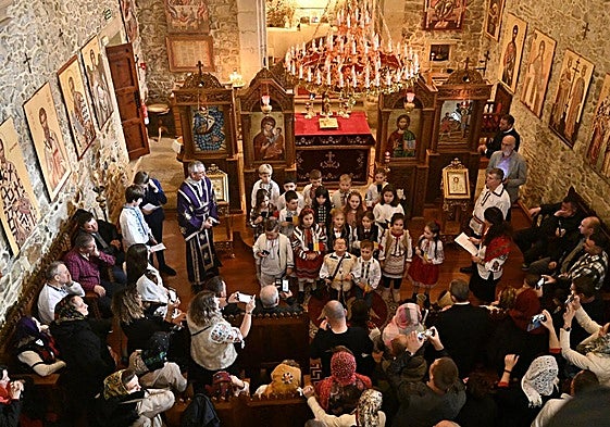 Fieles ortodoxos en la ermita de Uba de Martutene, mientras un coro de niños canta el himno de Rumanía frente al altar.