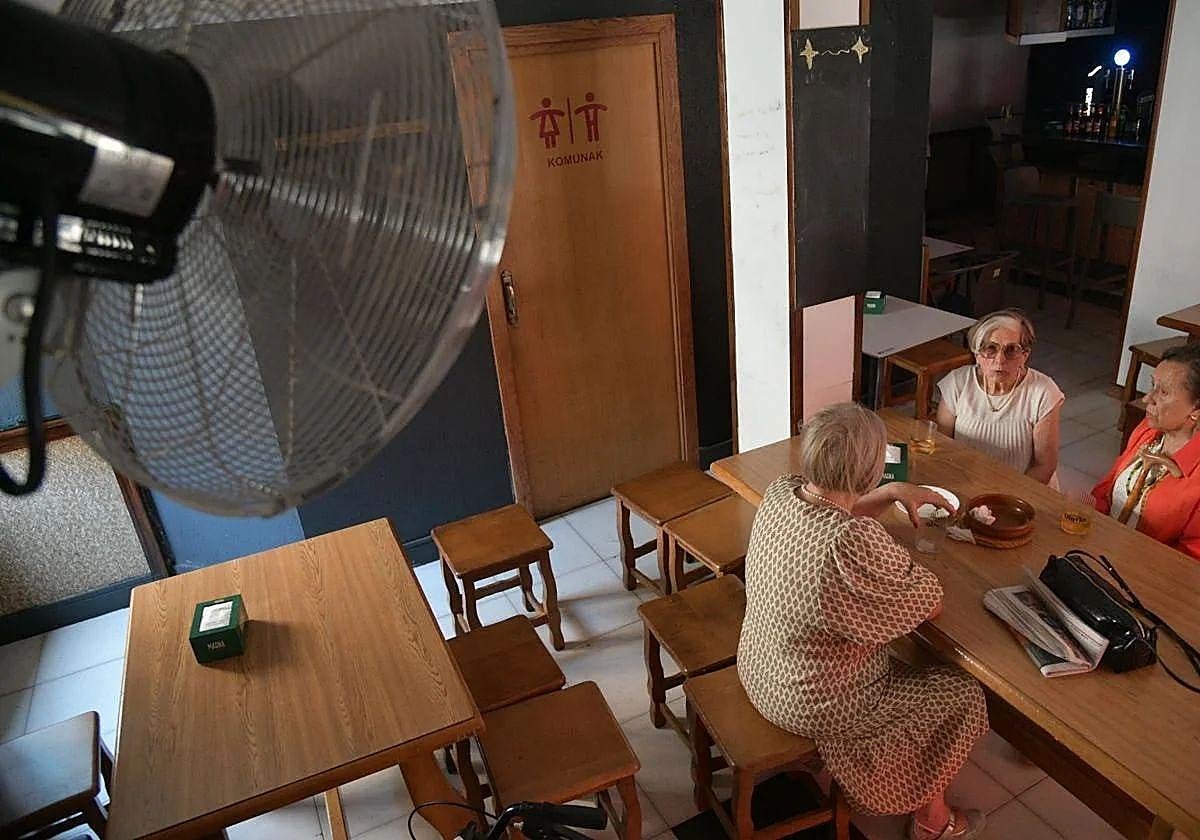 Varias mujeres se resguardan del sofocante calor dentro de un bar y bajo un ventilador.