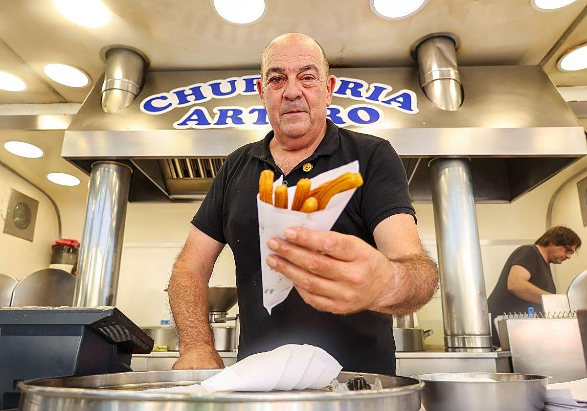 Arturo Manchado sirve media docena de churros a un cliente en su churrería de la Plaza Easo.