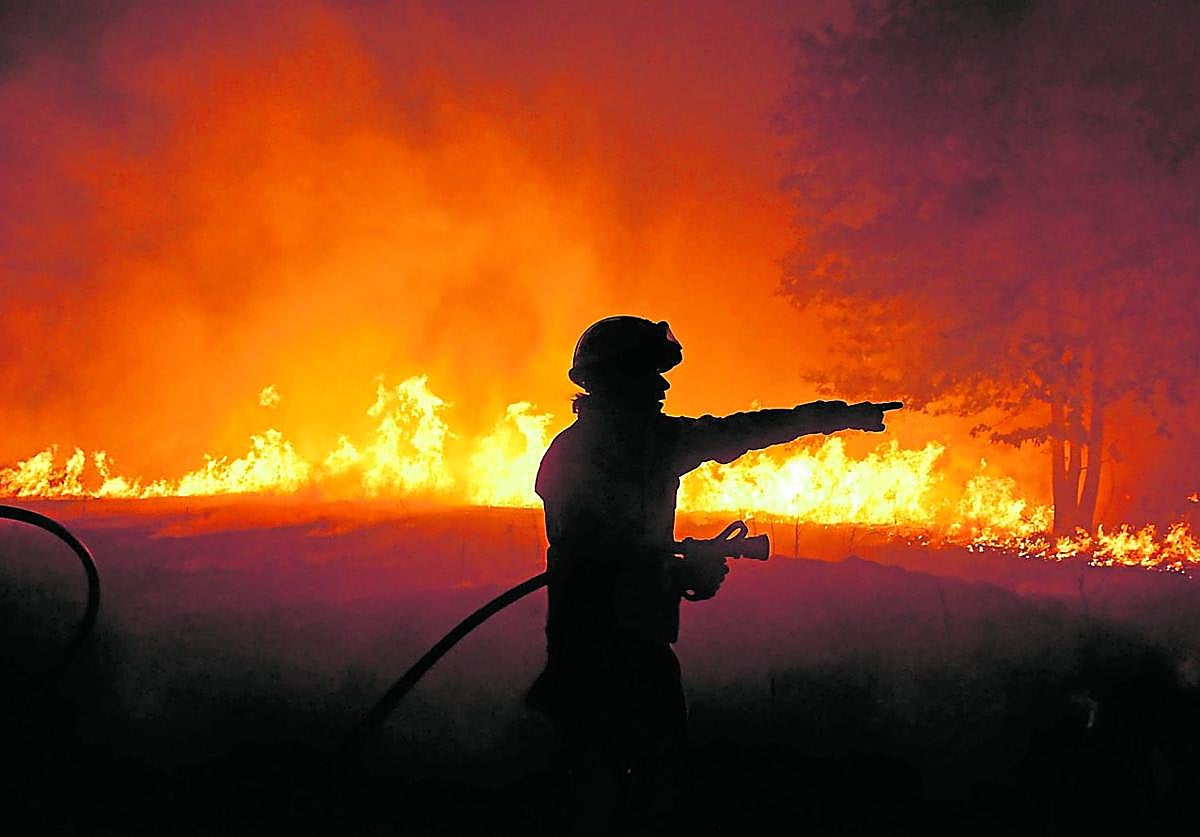 Un bombero da instrucciones para enfrentar el fuego en el incendio de Vileza (Orense).