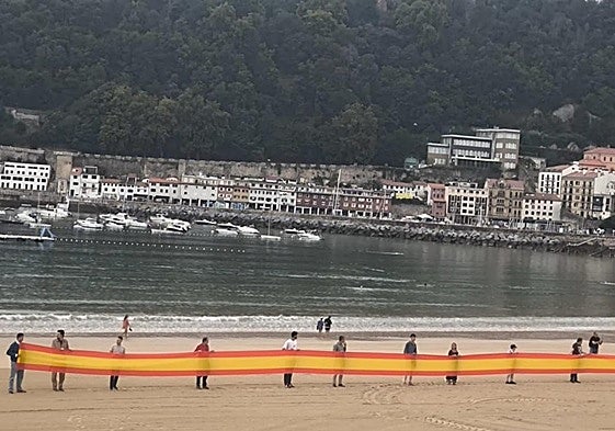 Los miembros de Vox agarran la bandera en el arenal donostiarra este martes.