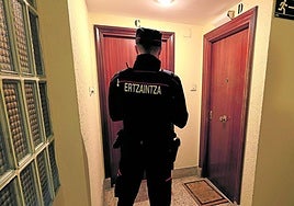 Un agente de la Ertzaintza inspecciona las puertas de dos viviendas en un bloque de Irun.