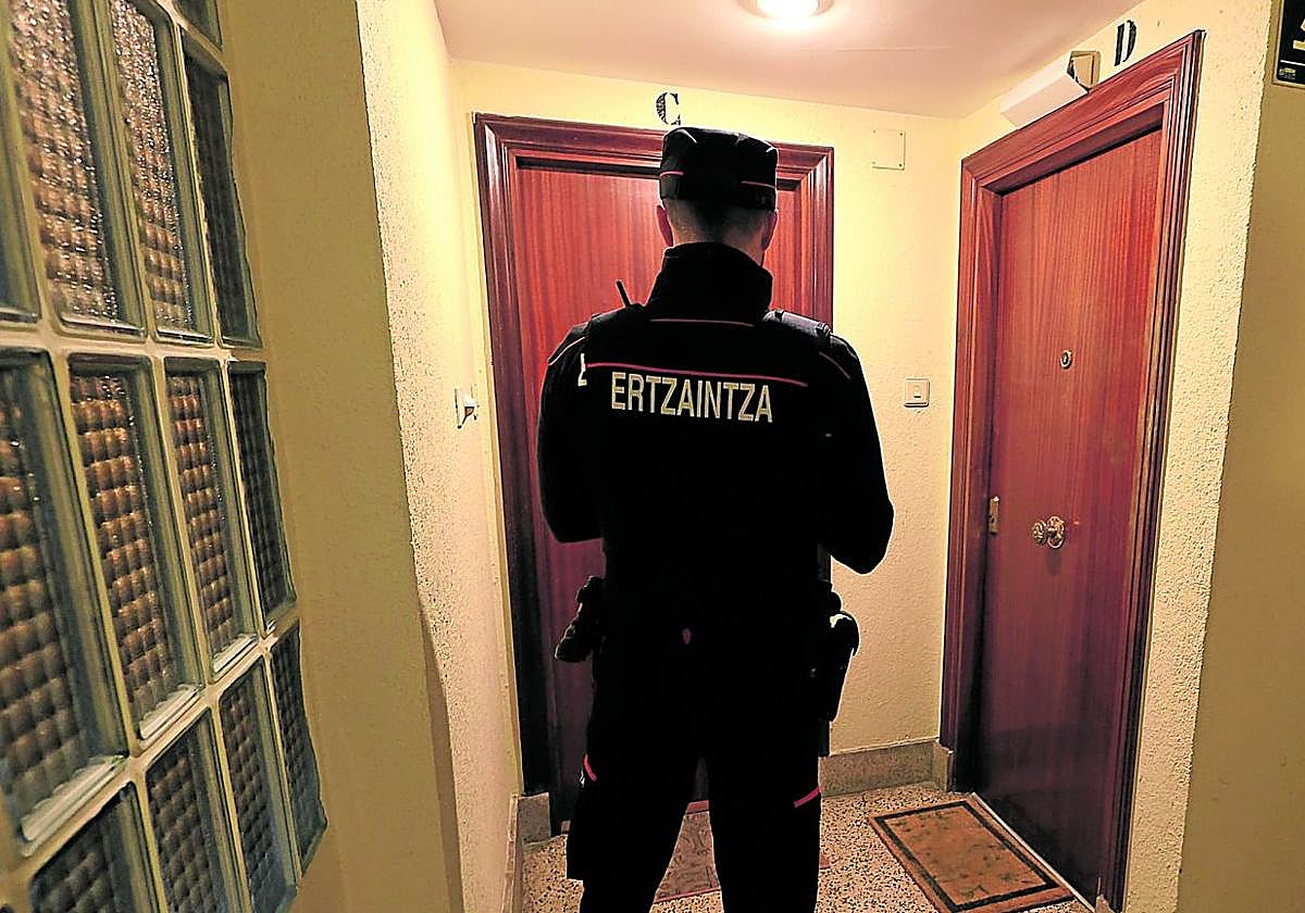 Un agente de la Ertzaintza inspecciona las puertas de dos viviendas en un bloque de Irun.