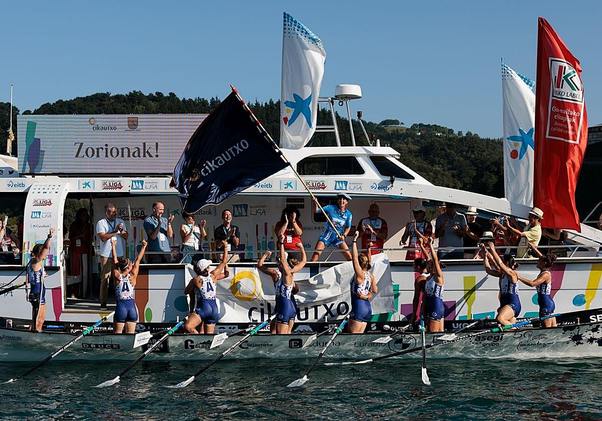 La plantilla titular de Arraun Lagunak ondea la Bandera de Ondarroa como celebración de la victoria y el título de liga.