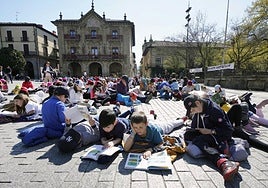 Un grupo de chavales leen en una plaza pública.