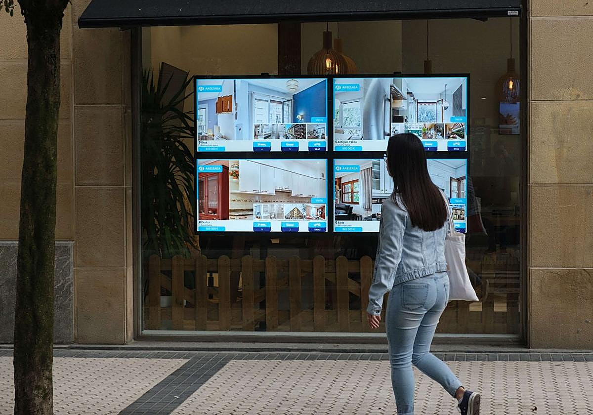 Una mujer pasa por delante del escaparate de una agencia inmobiliaria.