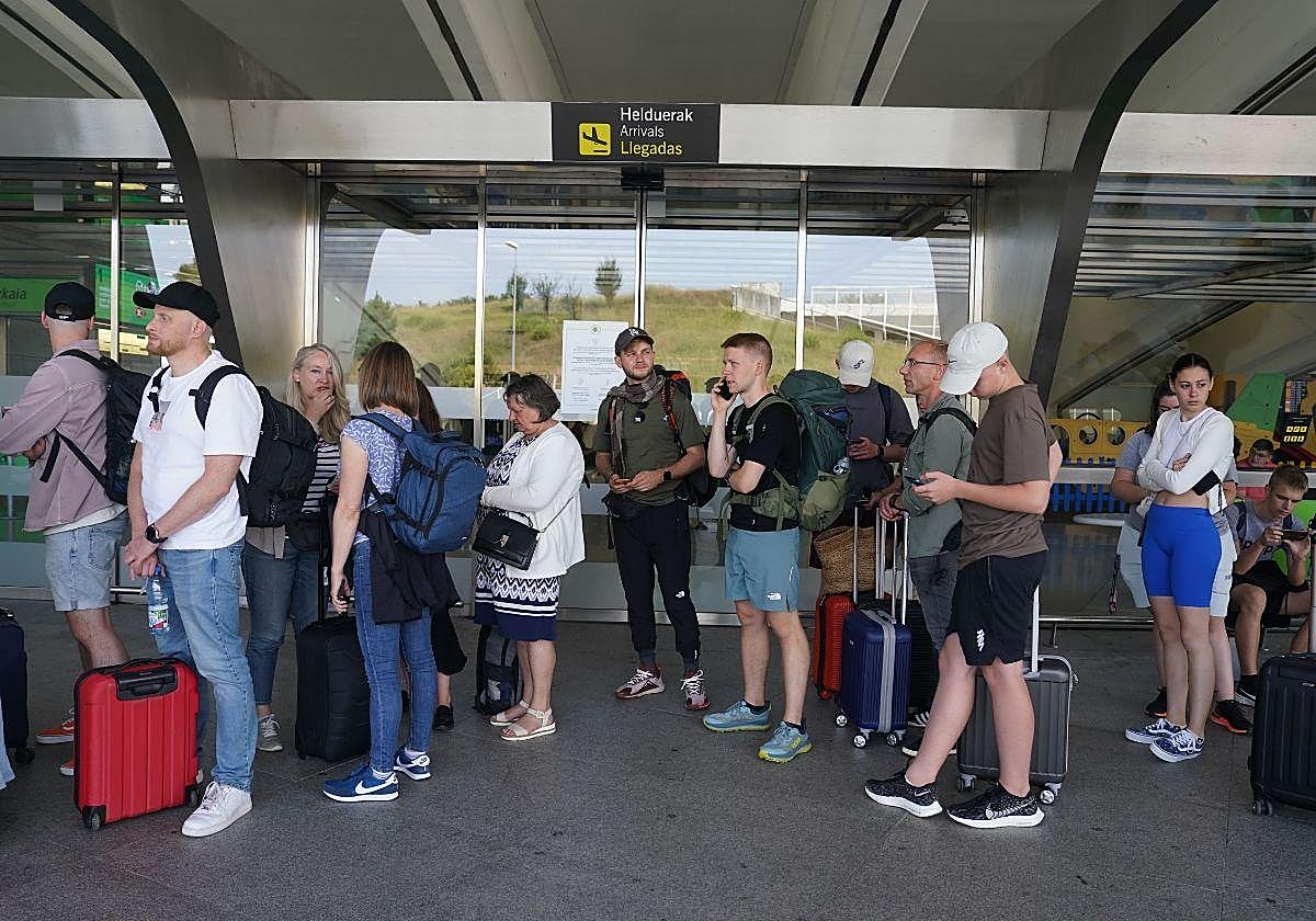 Varios pasajeros esperan a la llegada de autobuses en las inmediaciones del aeropuerto de Loiu en Bilbao.