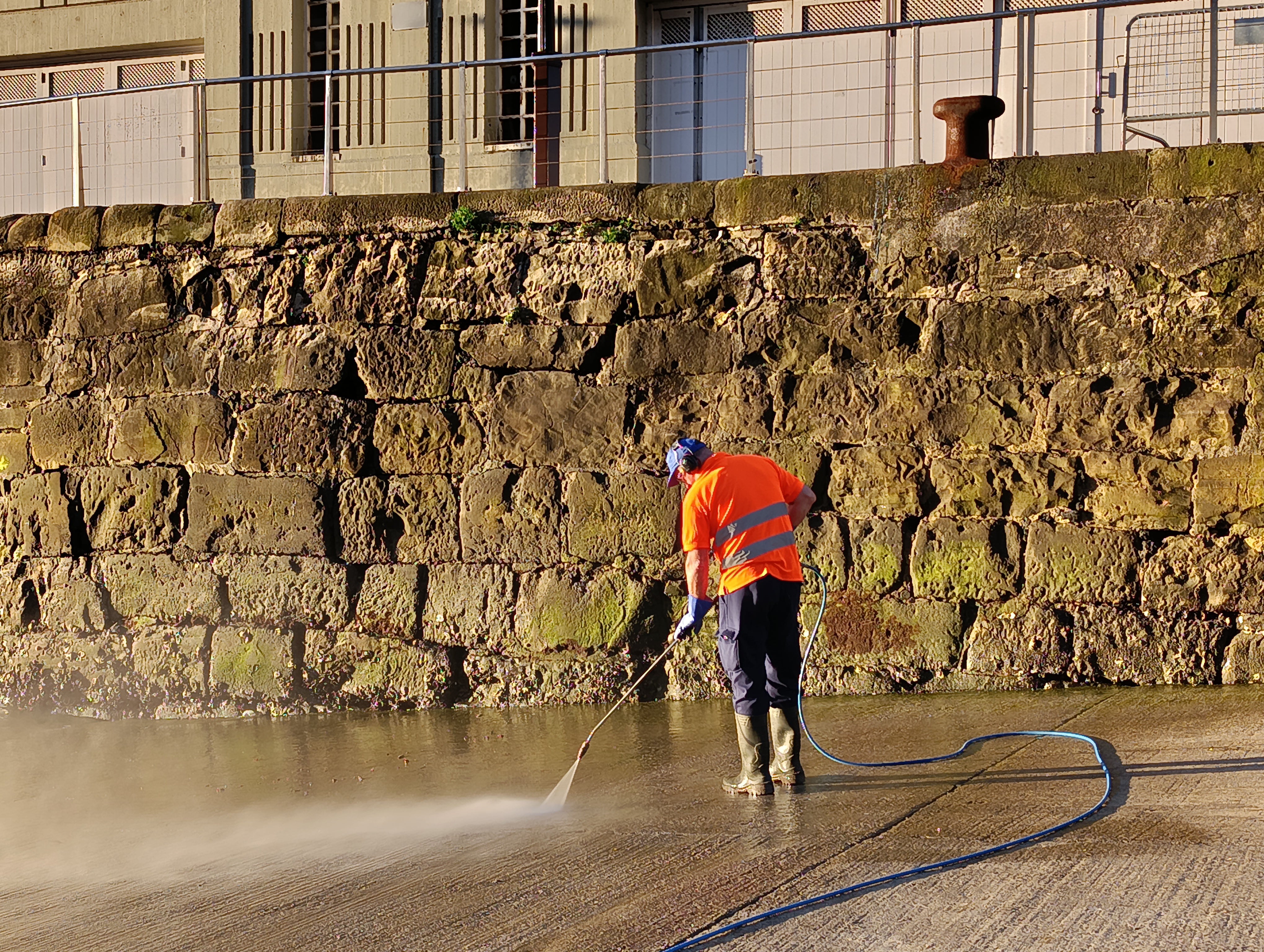 Un trabajador limpia las algas y verdines del puerto de Donostia.