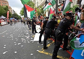 Ertzainas sujetan la valla tras la invasión de la protesta en favor de Palestina en la llegada de La Vuelta a Bilbao.