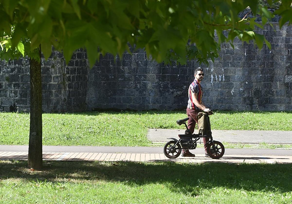 Un ciclista pasea con la bicicleta en mano por Zumardi Handi.