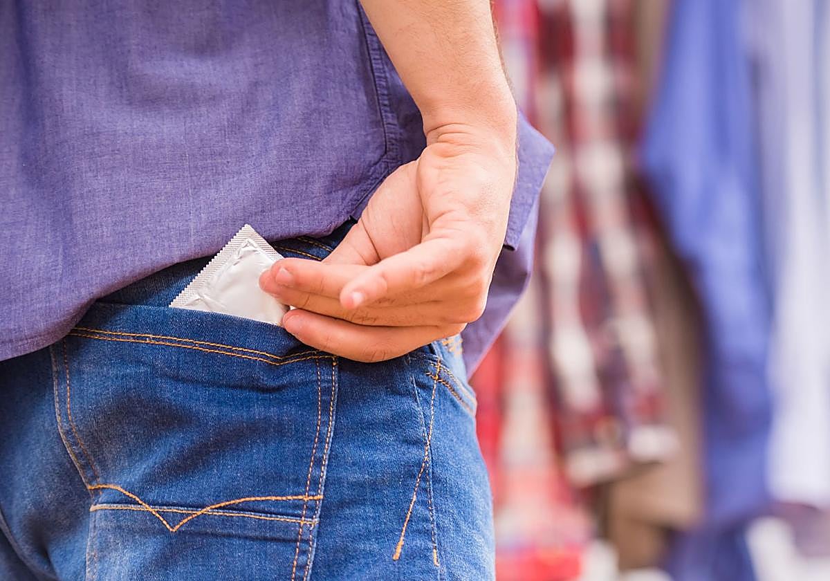 Un joven saca un preservativo del bolsillo.