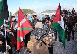 Una mujer porta una ikurriña y una bandera de Palestina, en una protesta contra el genocidio.