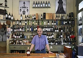 Bernardo Anabitarte posa detrás del mostrador y delante de las estanterías en Vinos Ezeiza.
