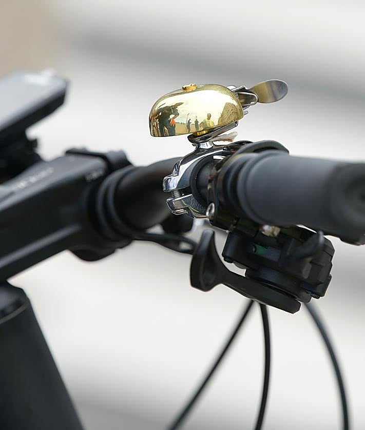 Imagen secundaria 2 - Utilizar el móvil y llevar auriculares está prohibido. Debajo, peatones invadiendo el bidegorri y un elemento obligatorio de la bicicleta, el timbre.