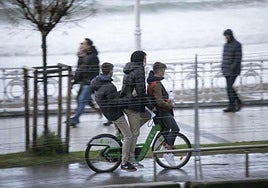 Tres chicos en una bicicleta junto a la playa de La Concha en una imagen de archivo.