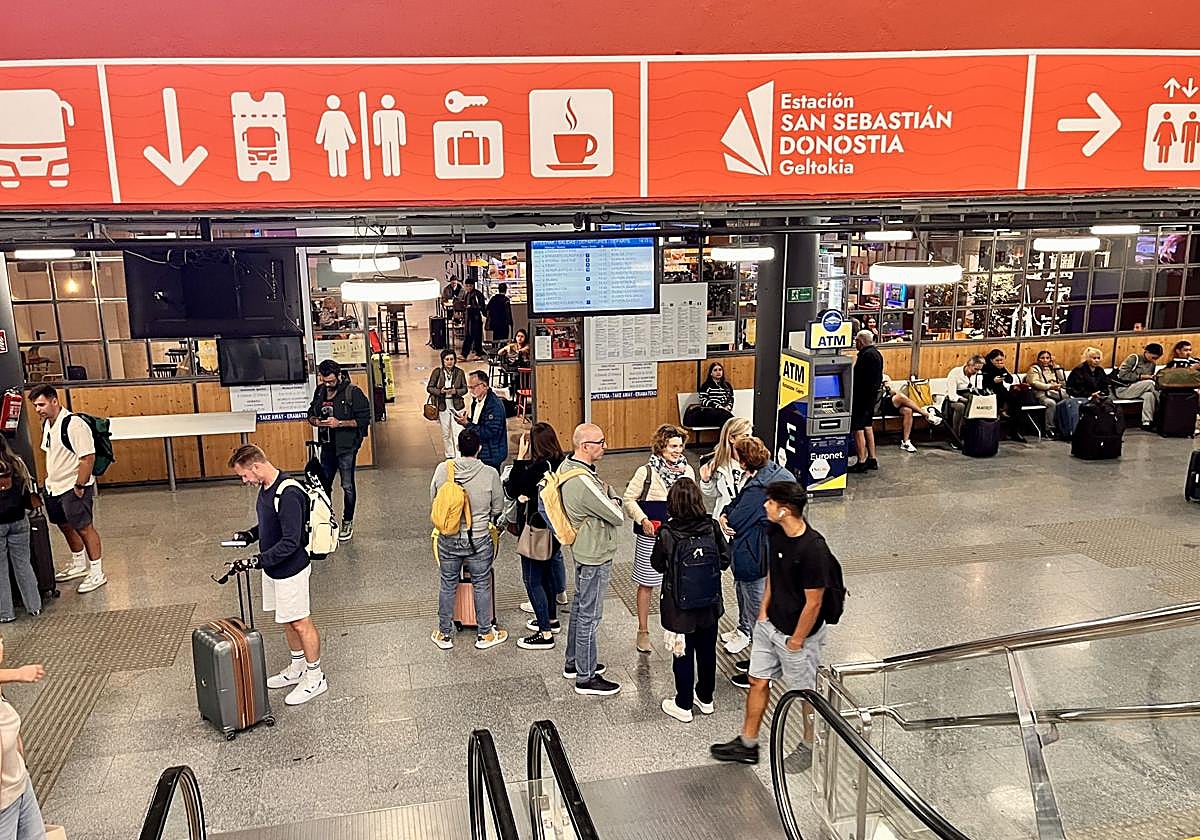 Viajeros en la estación de autobuses de San Sebastián, con la cafetería al fondo.