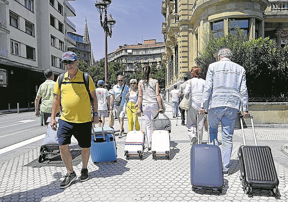 Turistas vienen y van con sus maletas por una céntrica calle de San Sebastián.