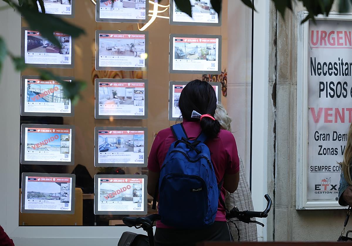 Una joven mira los anuncios de una inmobiliaria de Donostia.