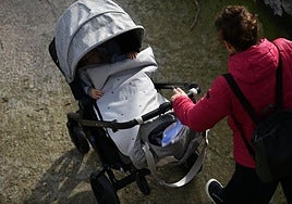 Una madre pasea a su hijo en un carrito de bebés.