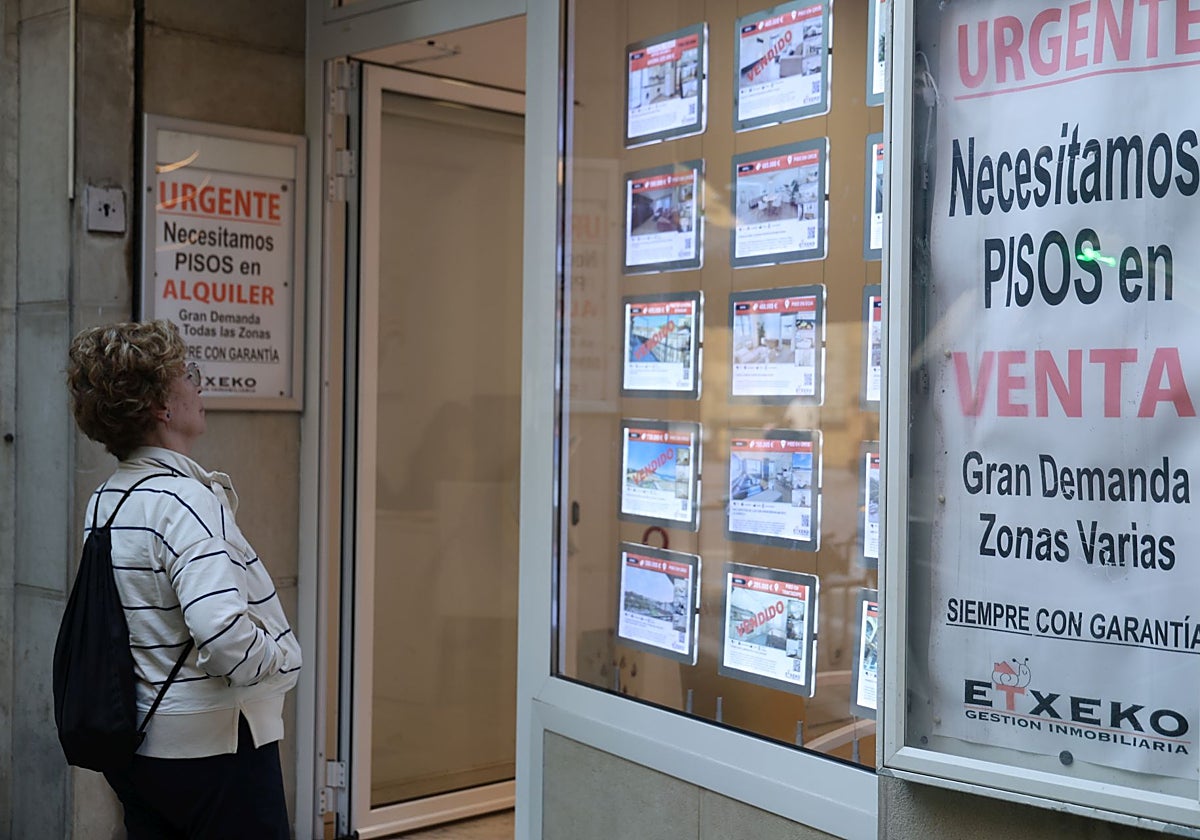 Una mujer observa una inmobiliaria que solicita pisos en venta y en alquiler en Donostia.