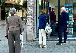 Un grupo de jubilados aguarda en la puerta de una agencia de viajes.