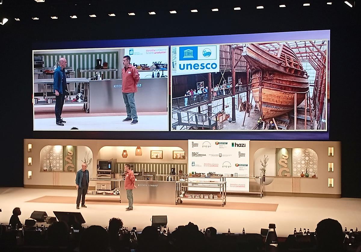 Aitor Arregi, del Elkano de Getaria, y Xabier Agote, presidente y fundador de Albaola de Pasaia, con la réplica de la Nao San Juan en pantalla.