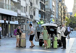 Varios turistas descargan sus maletas junto al Boulevard donostiarra para dirigirse a su hotel.