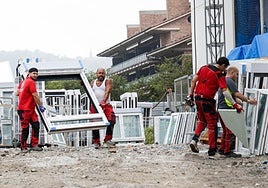 Varios operarios transportan unas ventanas para un edificio de VPO que se construye en Hondarribia.