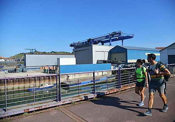 Dos personas caminan junto a las instalaciones de Astilleros Balenciaga en Zumaia.