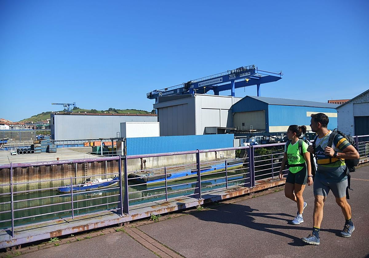 Dos personas caminan junto a las instalaciones de Astilleros Balenciaga en Zumaia.