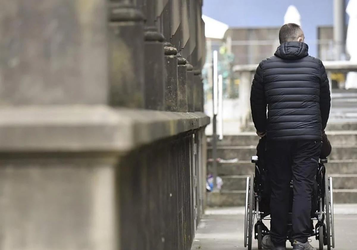 Imagen de una persona paseando con un familiar en silla de ruedas.