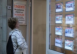 Una mujer ante el escaparate de una inmobiliaria que reclama pisos en alquiler ante una demanda que supera con creces la oferta.