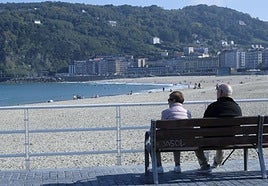 Dos personas observan desde un banco el aspecto de la playa de la Zurriola, con cielos despejados.