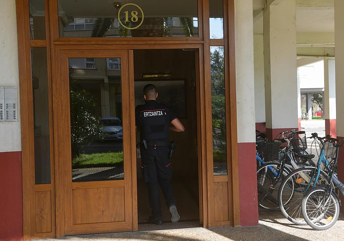 Un ertzaina entrando al edificio donde reside el presunto homicida.