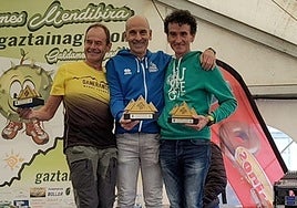 Jexux Zelaia, podioan, lehiakideekin eta saria eskuetan duela.