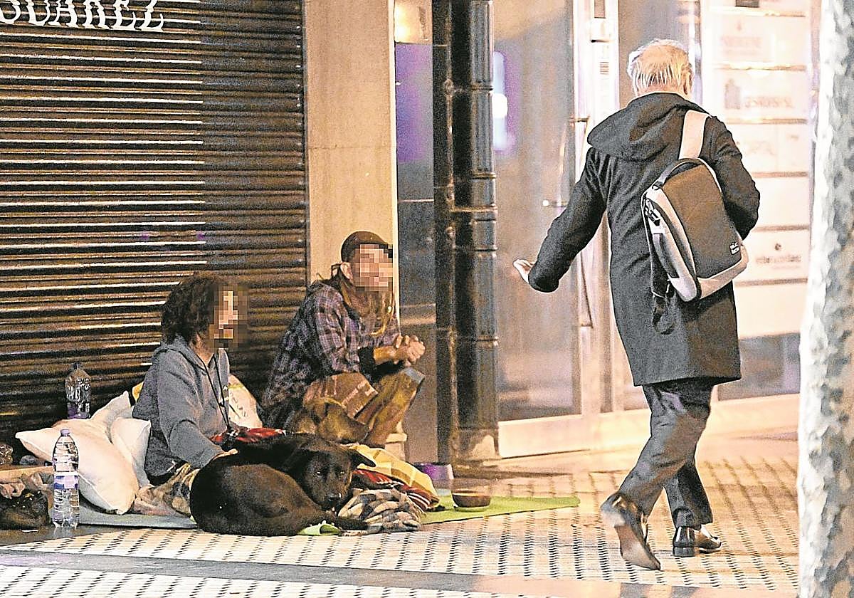 Dos personas 'sintecho' piden limosna en las calles de Donostia.