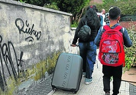 Una de las afectadas transporta junto a su hijo una maleta con los enseres que recogieron de la casa.