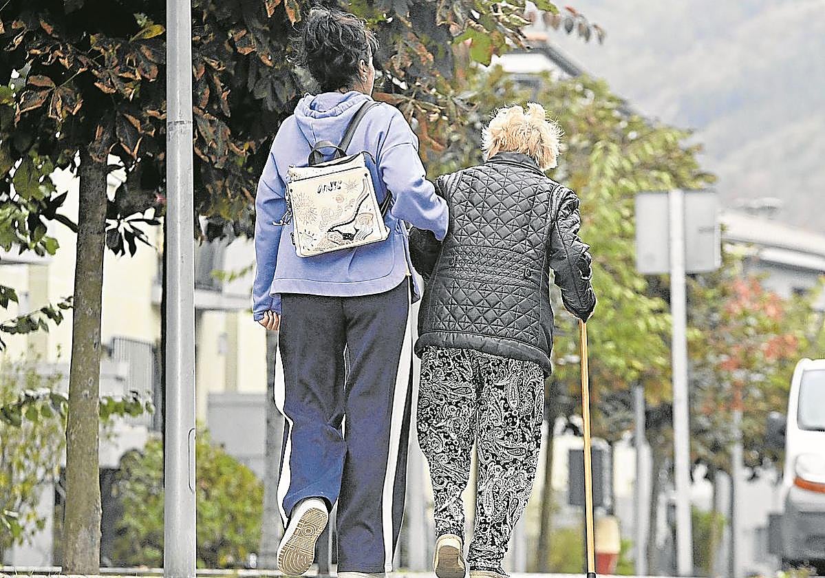 Una mujer ayuda a caminar a una persona mayor en una localidad guipuzcoana.