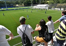 Padres presenciando un partido de fútbol base.