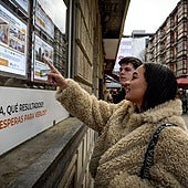 Dos jóvenes miran la fachada de una inmobiliaria en Bilbao.