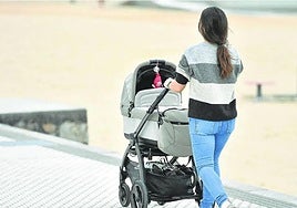 Una madre pasea a su bebé en un carrito junto a la playa de Ondarreta.