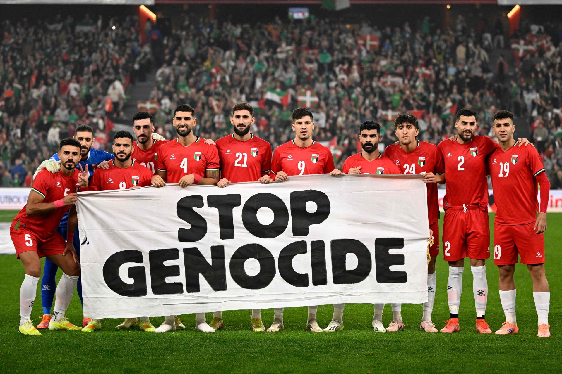 Imagen principal - La selección de Palestina, con la pancarta antes del partido.