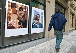 Un joven guipuzcoano pasea frente a una entidad bancaria que ofrece una hipoteca.