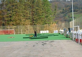 Operario instala la alfombra en el pavimento para el caucho y las briznas