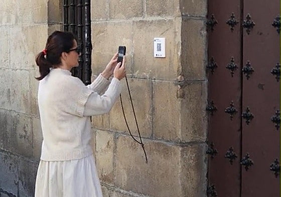 Una mujer escanea con su teléfono móvil el código QR habilitado a las puertas de un edificio.