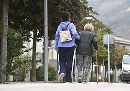 Una mujer mayor es acompañada por una cuidadora en Olaberria.