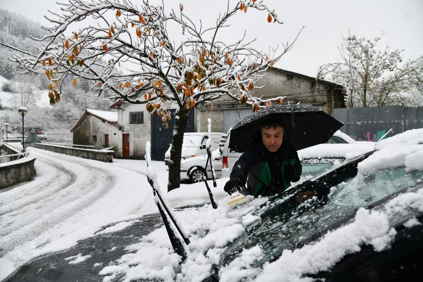 Un hombre quita, como puede, la nieve caída en su vehículo. 